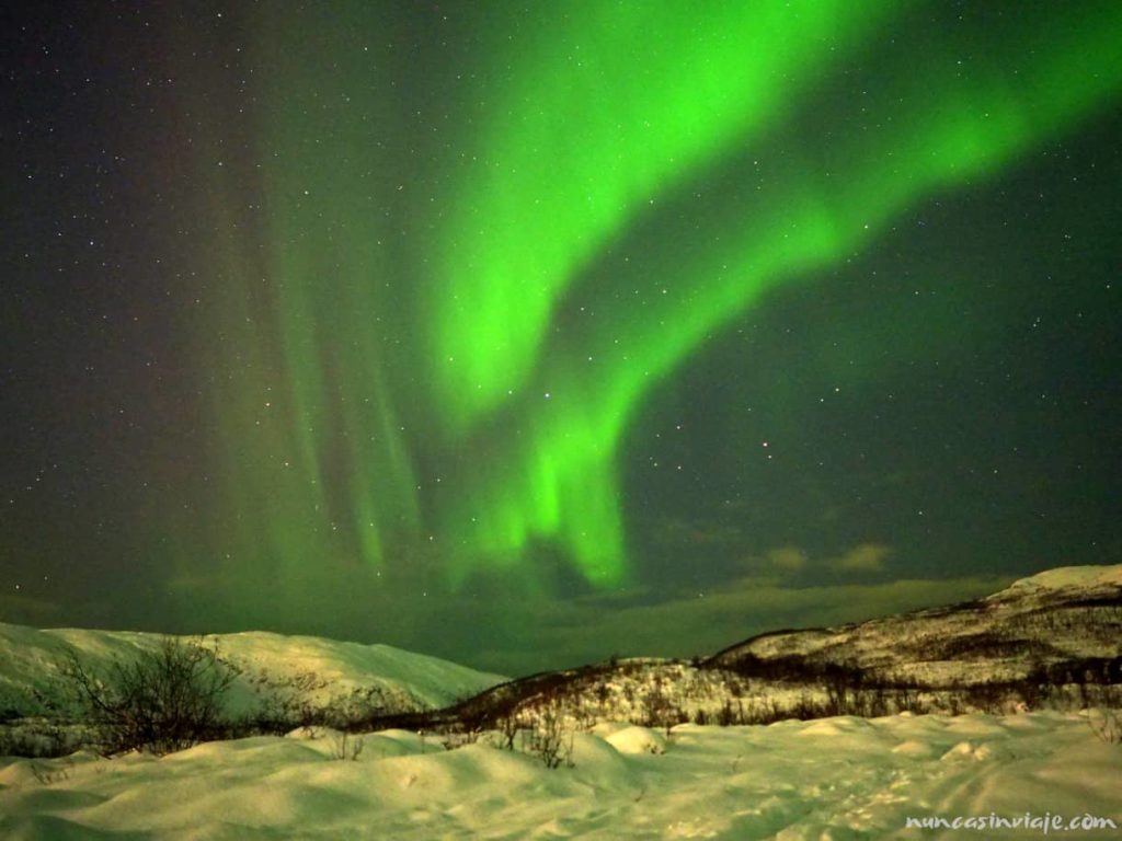 Una aurora boreal verde sobre una montaña nevada