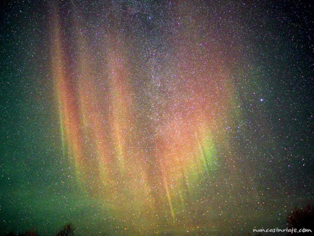 Una aurora boreal de colores sobre un cielo lleno de estrellas