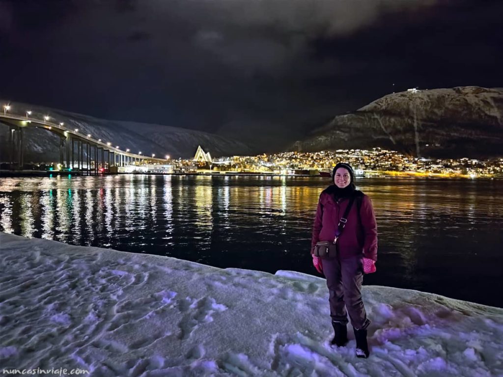 Zona del puerto de Tromso con el puente y la Catedral del Ártico al fondo durante la noche